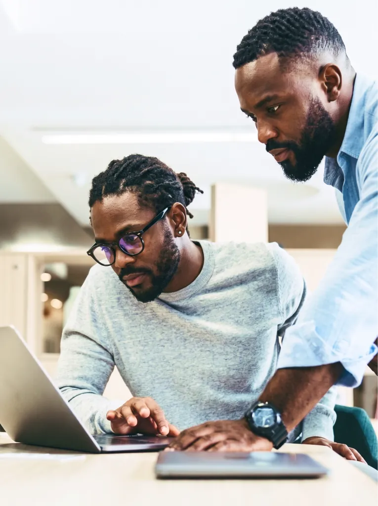 Two engineers reviewing work on a laptop